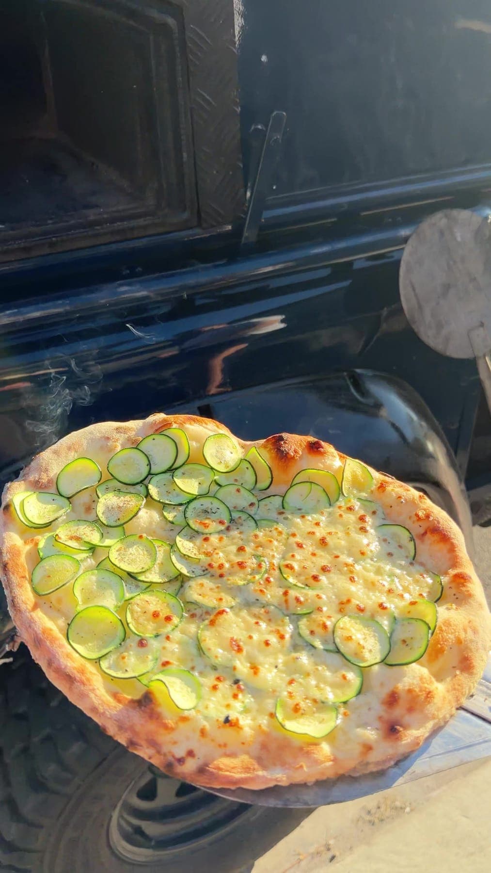 A zucchini pizza fresh out of the oven on a peel