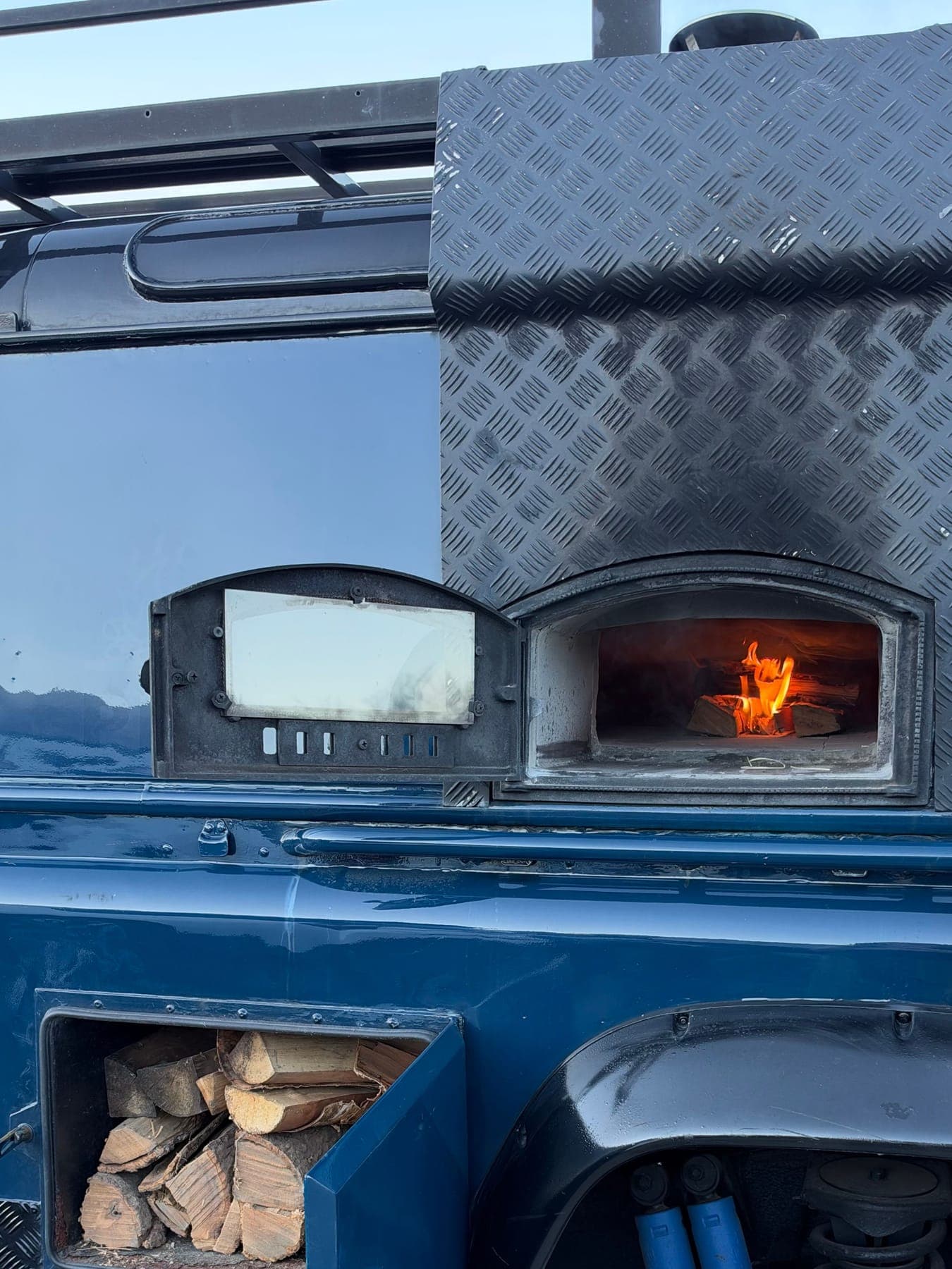 The oven lit, with the woodpile stacked below