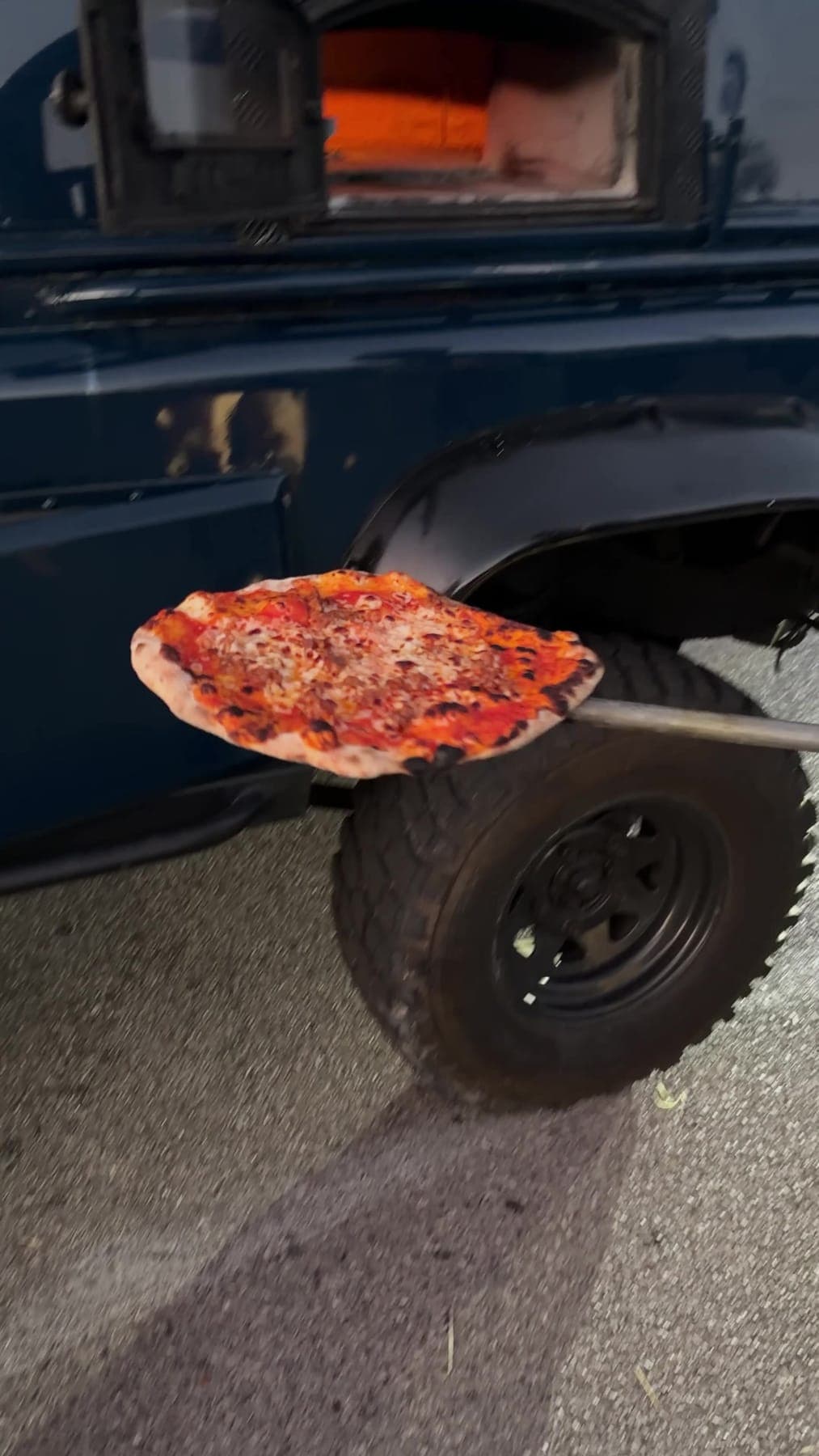 A pizza coming out of the oven on the peel