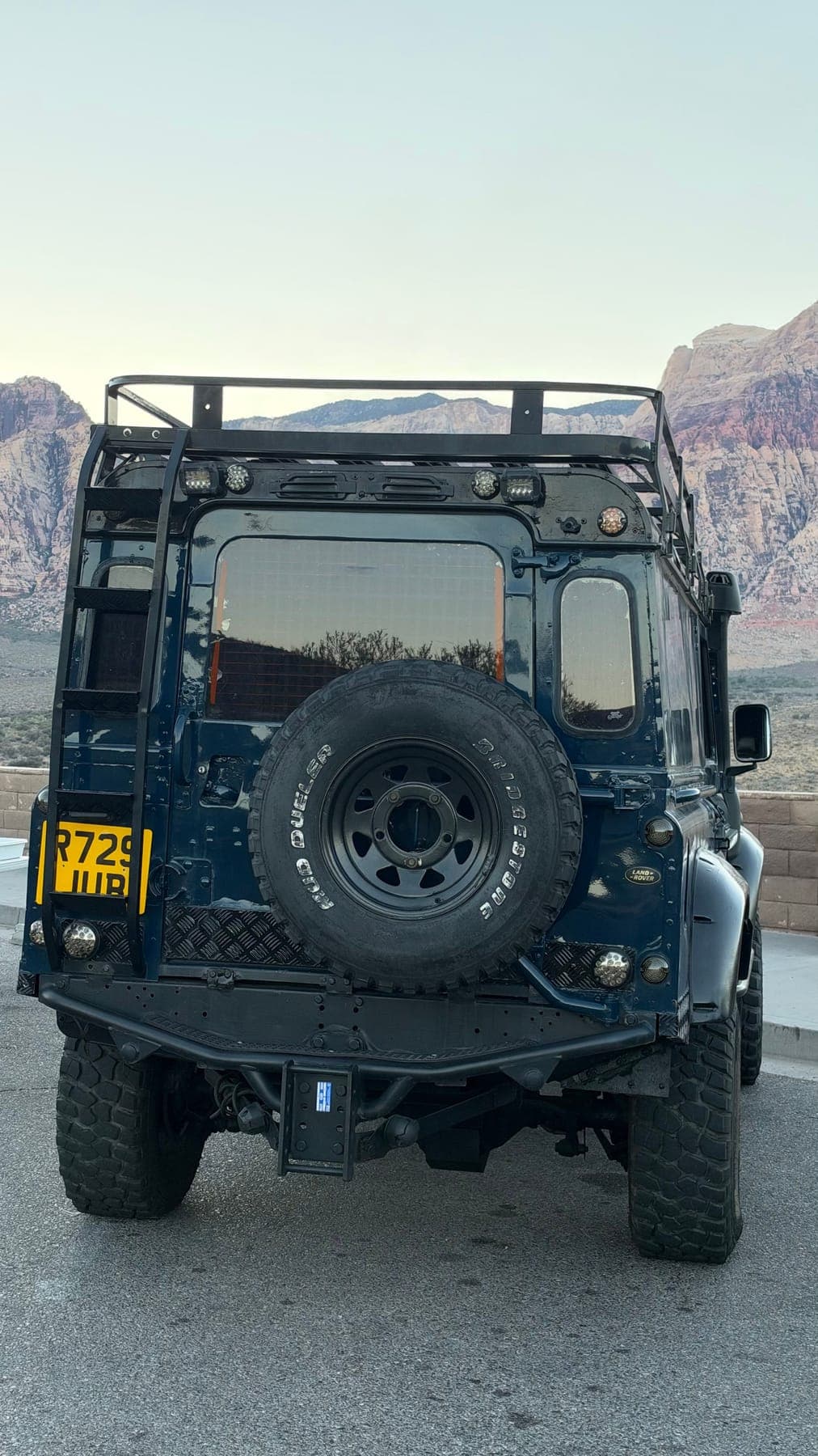 The rear of the truck with its yellow British plate and the Red Rock escarpment behind