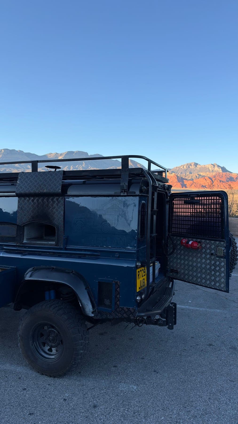The rear three-quarter of the truck with the red rocks in the evening light